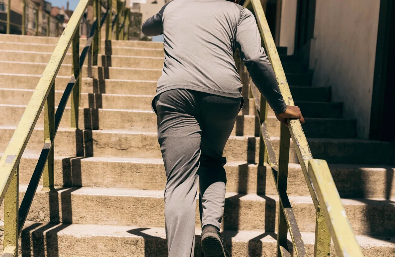 Hombre caminando escaleras arriba en ropa deportiva neutra durante el día